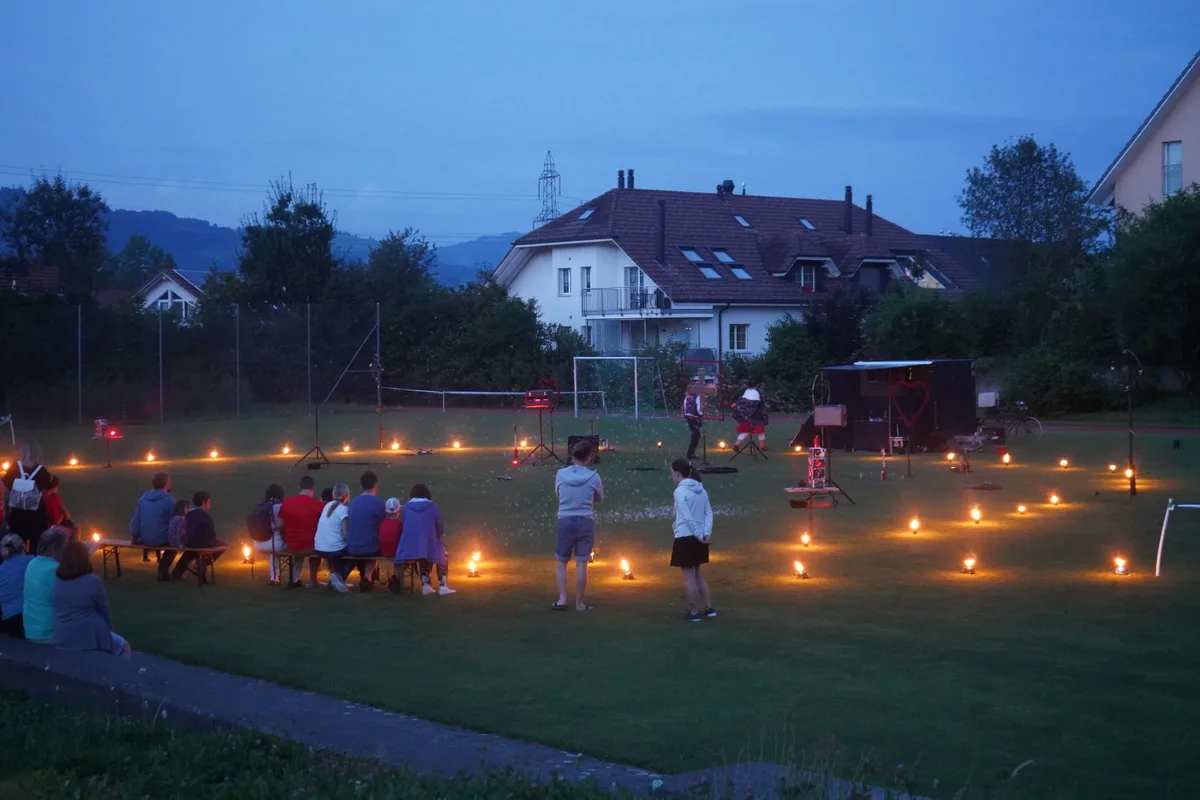 Ein Ring aus kleinen Petroleumlampen und Zuschauer, die warten.